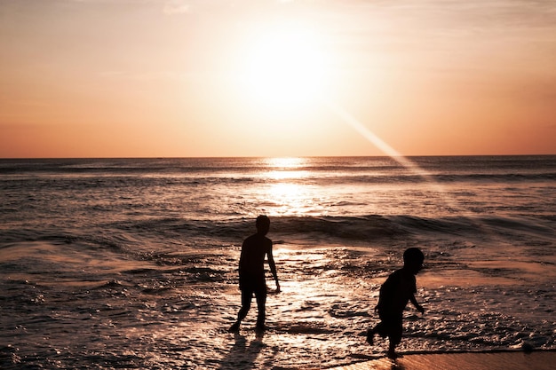 Silhouette di bambini su bella vista del cielo al tramonto sulla spiaggia