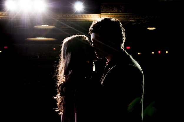 Silhouette of couple kissing while standing on the stage in the theatre