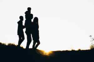 Free photo silhouette of a family walking by the sunset time