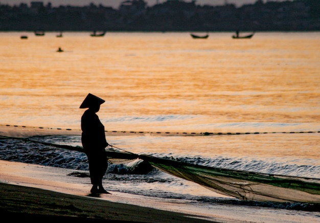 Silhouette of a fisherman with a boat on a coast