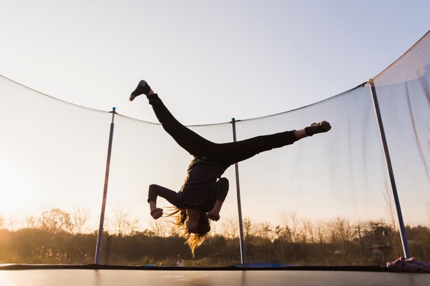 Silhouette of girl jumping on a trampoline doing split