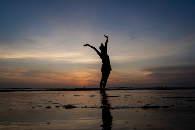 Силуэт девушки, стоящей в воде с поднятыми руками, жесты