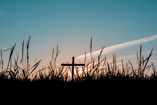 Free photo a silhouette of a handmade cross in the field