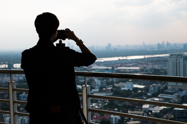 Free photo silhouette man taking photo of city