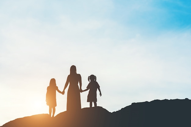 Silhouette of mother with her daughter standing and sunset