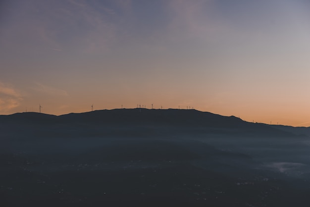 Silhouette of a mountain with windmills on the top