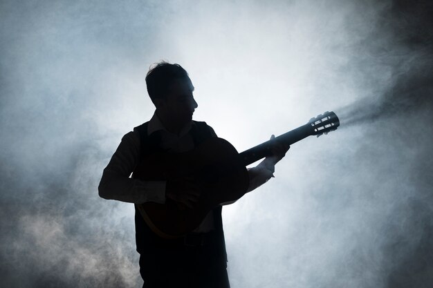 Silhouette of a musician on stage playing the guitar