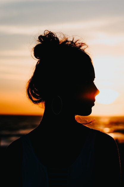 無料写真 美しい夕日と海の海岸に立っている女性のシルエット