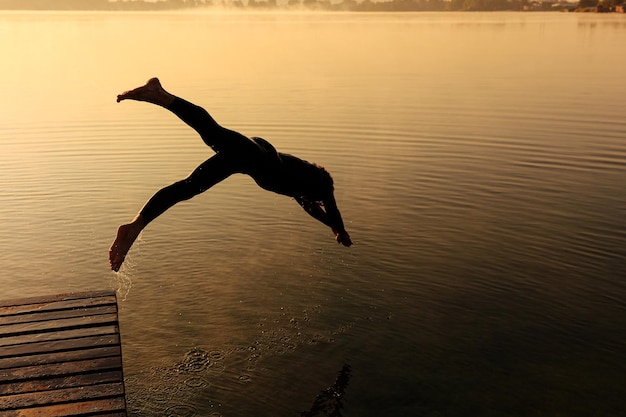 무료 사진 안개 낀 호수로 뛰어드는 활동적인 스포츠맨의 실루엣