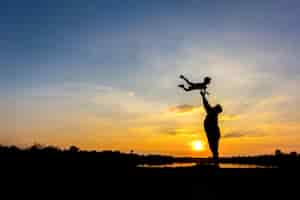 無料写真 空に息子を投げる父のシルエット。 、夕日の背景に父と息子