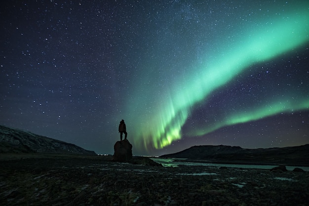 Foto gratuita sagoma di persona sotto l'aurora boreale