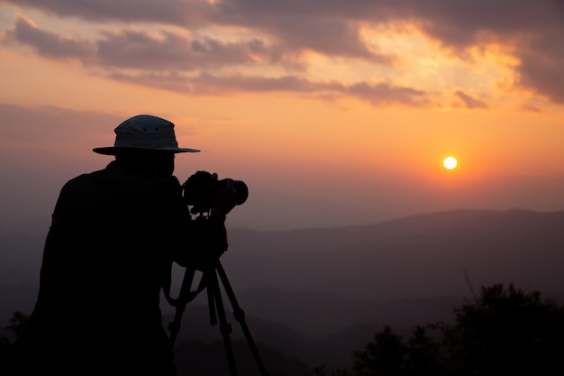 silhouette of a photographer who shoots a sunset in the mountains