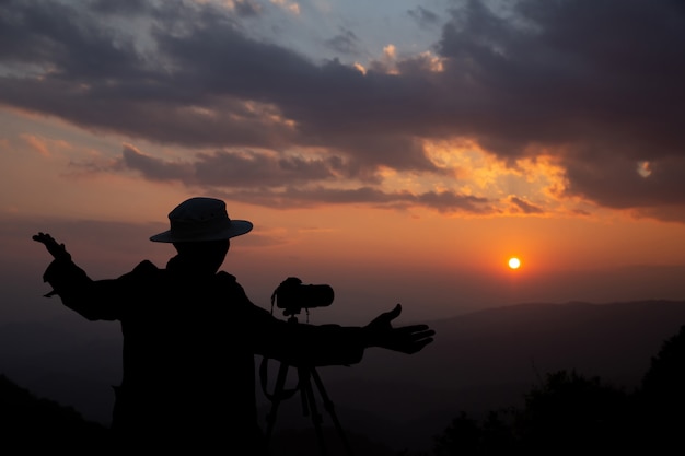 silhouette of a photographer who shoots a sunset in the mountains