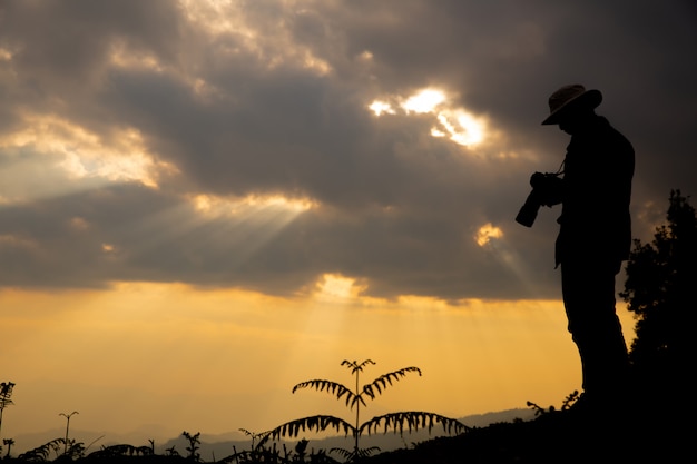 silhouette of a photographer who shoots a sunset in the mountains