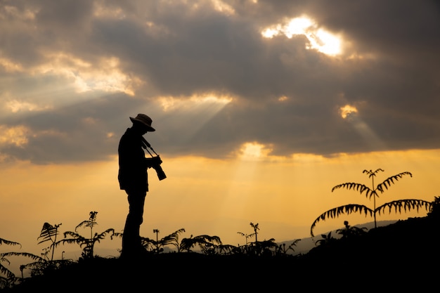 silhouette of a photographer who shoots a sunset in the mountains