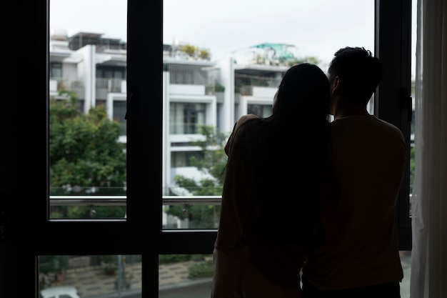 Silhouette of romantic couple embraced at home and looking through window