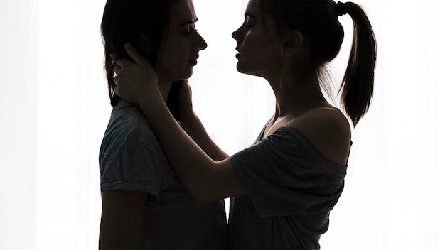 Free photo silhouette of romantic young lesbian couple loving against white background