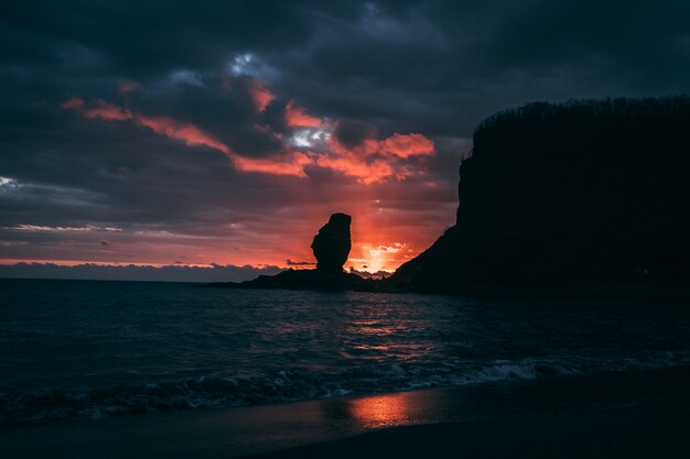 ニューカレドニアのカラフルな夕日に対する海食柱のシルエット