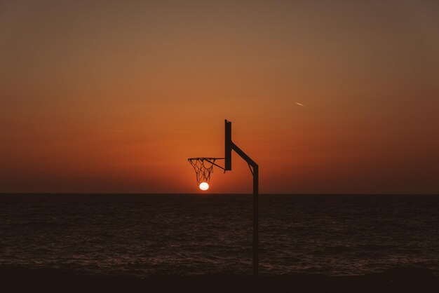 Silhouette shot of setting sun in a basketball hoop - perfect for wallpaper