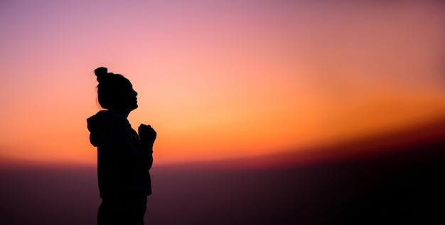 Силуэт сбоку портрет женщины, молящейся и смотрящей на закат с копировальным пространством