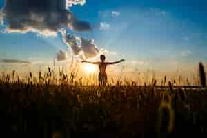 Free photo silhouette of sportive girl practicing yoga in field at sunrise.