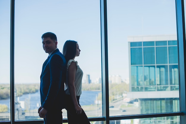 Silhouette of two business people leaning against each other