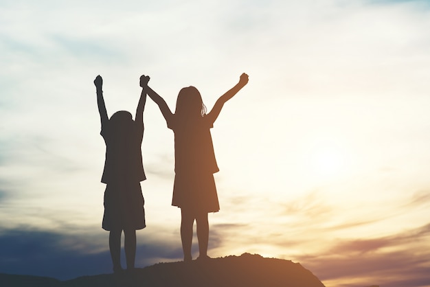 Silhouette of two girl having fun in nature Free Photo