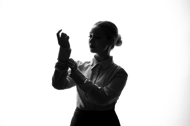 Silhouette of woman fixing buttons on her shirt shadow back lit young