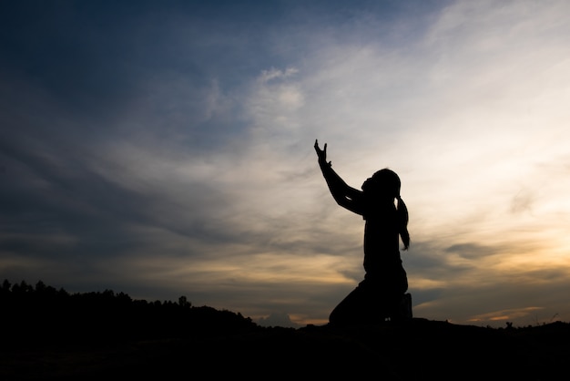 Silhouette of woman praying with god
