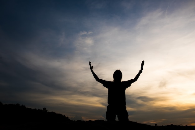 Silhouette of woman praying with god