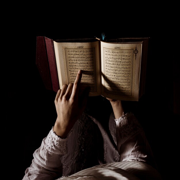 Silhouette of woman reading in quran