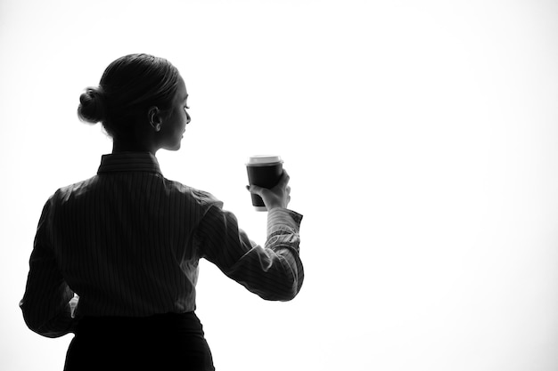 Silhouette of woman with delivery coffee in her hands shadow back lit young