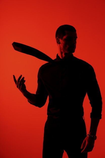 Silhouette of a young confident handsome businessman wearing black shirt in red light