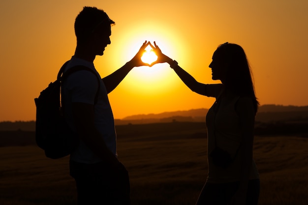 Silhouette of young couple in field.