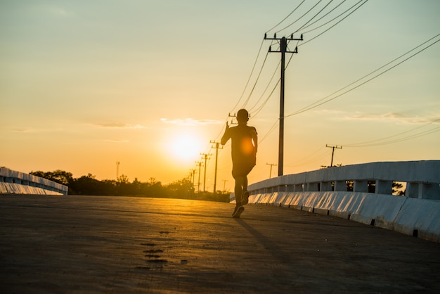 silhouette of a young fitness man running on sunrise