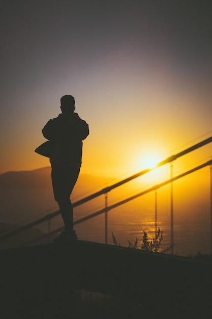 아름다운 일몰을 볼 수있는 계단 레일 뒤에 계단을 걷는 젊은 남성의 실루엣