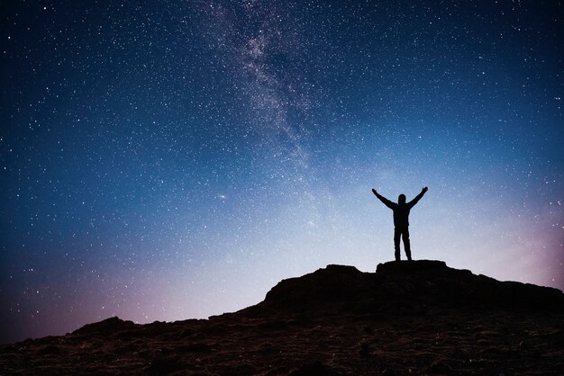 Silhouette young man background of the Milky Way galaxy on a bright star dark sky tone