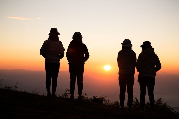 Silhouette of young woman are standing on top of the mountain relaxing 
