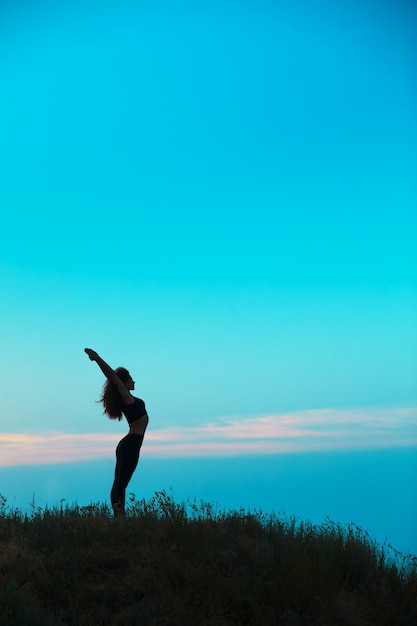 The silhouette of young woman is practicing yoga