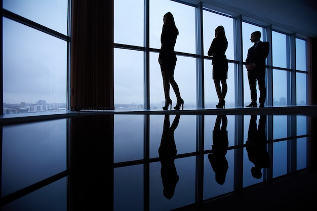 Free photo silhouettes of employees looking through windows