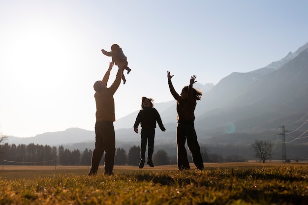 Foto gratuita sagome di famiglie in natura al tramonto