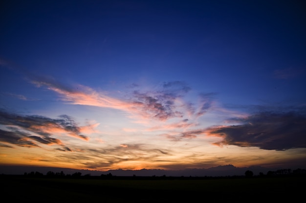 美しい夕日の曇り空の下の丘のシルエット