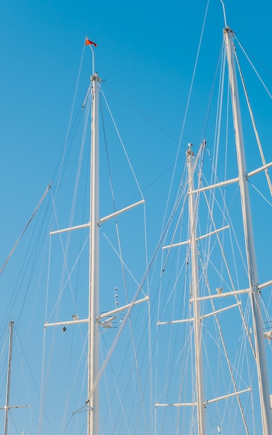 Силуэты матчевых яхт в гавани на фоне ясного голубого неба идея вертикальной рамки для фона или новостей о яхтинге