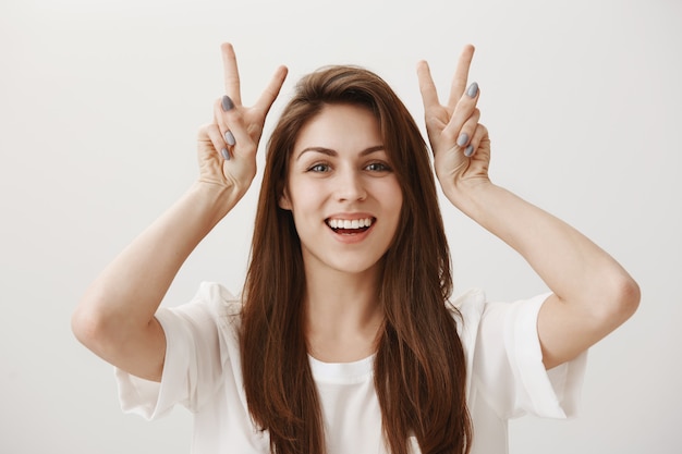 Silly adorable girl showing quotation marks gesture and smiling happy