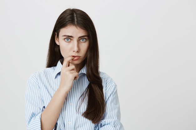 Silly adult woman biting finger, looking shy