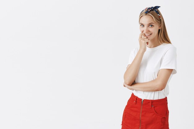 Silly beautiful young blond girl posing against the white wall