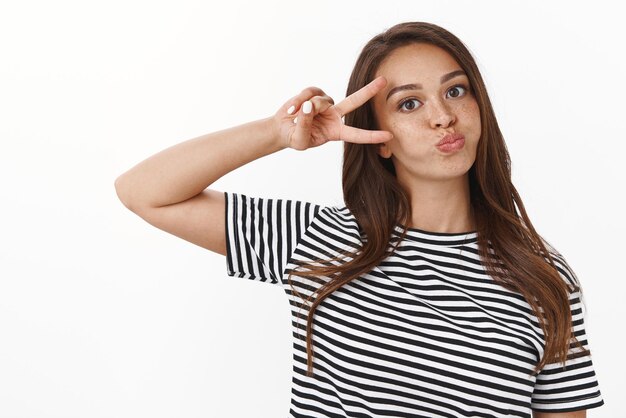 Silly carefree cute girlfriend fool around enjoy dayoff having fun making childish faces holding breath and showing peace or victory sign playfully enjoy time with friends white background