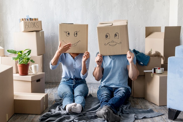 Free photo silly couple at home on moving day with boxes over head