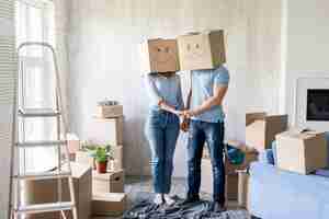 Free photo silly couple with boxes over heads holding hands on moving out day