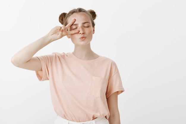 Silly and cute teenage girl posing against the white wall